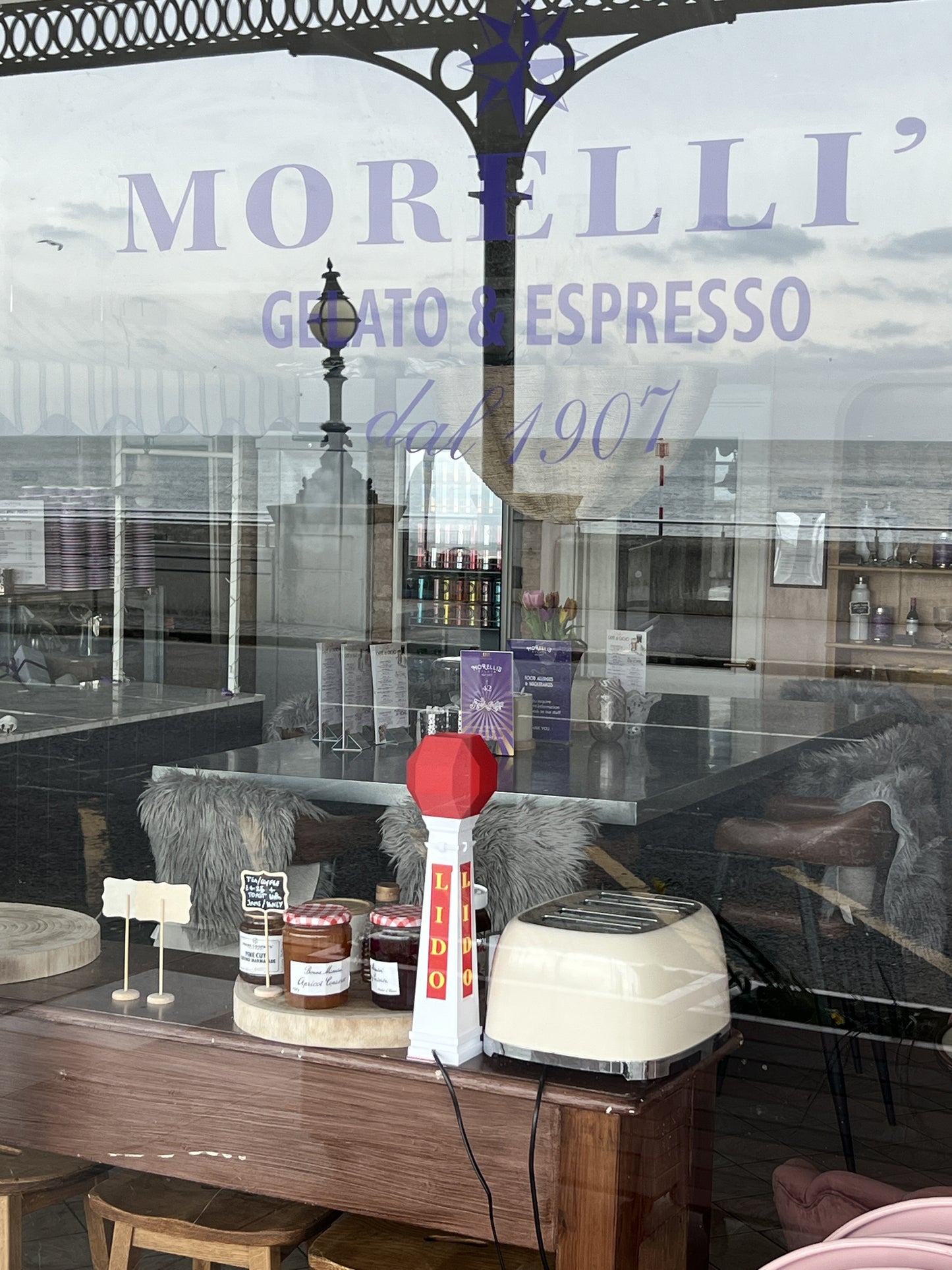 Morrelli Espresso shop window with reflections of a barista and coffee equipment.